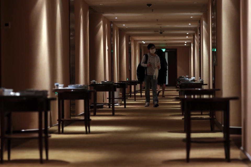 A masked foreign journalist who was selected to cover the opening ceremony of the Chinese People's Political Consultative Conference (CPPCC) walks by breakfast placed on the tables outside each room assigned for journalists in Beijing, Thursday, May 21, 2020. China is strictly limiting the number of journalists who can cover its ongoing legislative session because of the coronavirus outbreak. (AP Photo/Andy Wong)