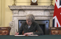 Britain's Prime Minister Theresa May signs the official letter to European Council President Donald Tusk, in 10 Downing Street, London, Tuesday March 28, 2017, invoking Article 50 of the bloc's key treaty, the formal start of exit negotiations. Britons voted in June to leave the bloc after four decades of membership. (Christopher Furlong/Pool Photo via AP)