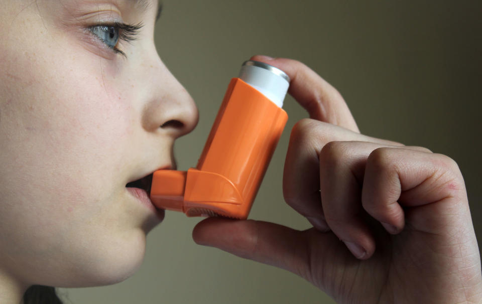 A girl uses an asthma puffer.