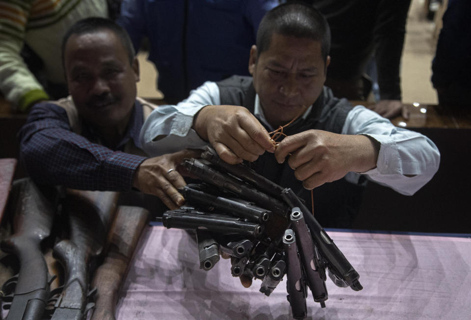 Assam police personnel tie together pistols laid down by different rebel groups during a surrender ceremony in Gauhati, India, Thursday, Jan. 23, 2020. More than 600 insurgents belonging to eight different rebel groups have surrendered to Indian authorities in this troubled northeastern state, responding to the government’s peace initiative to rejoin mainstream society. (AP Photo/Anupam Nath)