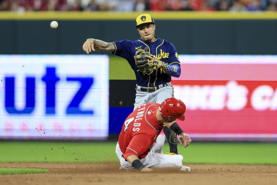 Milwaukee Brewers' Kolten Wong, top, forces out Cincinnati Reds' Matt Reynolds, bottom, as he throws to first base to turn a double play during the sixth inning of a baseball game in Cincinnati, Friday, Sept. 23, 2022. (AP Photo/Aaron Doster)