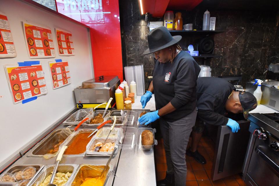 Lakita Spann prepares a baked potato order as her husband and chef, Aaron, shuttles food from the back kitchen to the front of their Mr. Potato Spread restaurant in the Orange Park Mall food court on Wednesday.