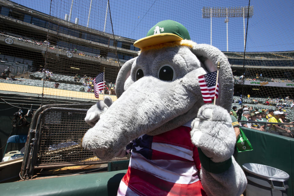 Oakland Athletics mascot "Stomper" waves a pair of United States flags before a baseball game against the Boston Red Sox, Sunday, July 4, 2021, in Oakland, Calif. (AP Photo/D. Ross Cameron)