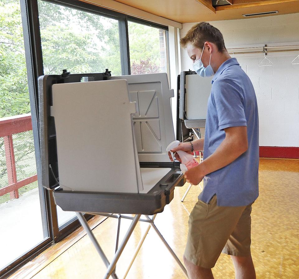 Milton High graduate Bobby Carew, 18, cleans each voting booth after use at the Cunningham Community Center in Milton.