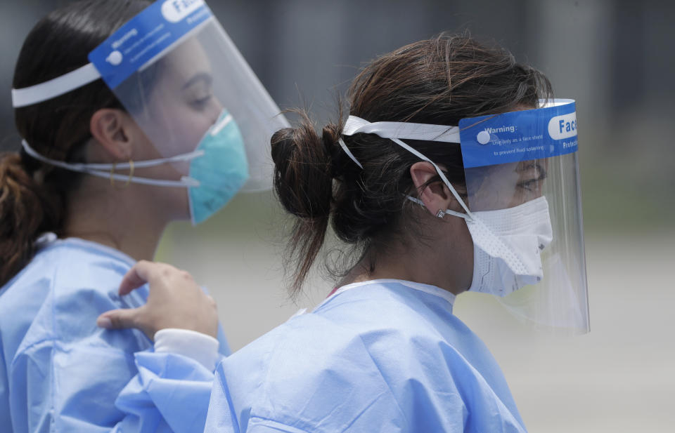 Healthcare workers walk to a tent, Wednesday, Aug. 5, 2020, at a COVID-19 testing site outside Hard Rock Stadium in Miami Gardens, Fla. State officials say Florida has surpassed 500,000 coronavirus cases. Meanwhile, testing is ramping up following a temporary shutdown of some sites because of Tropical Storm Isaias. (AP Photo/Wilfredo Lee)