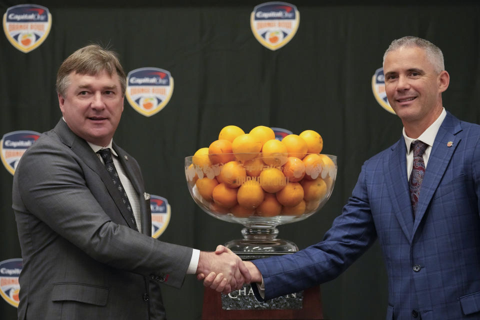 Georgia head coach Kirby Smart, left, and Florida State head coach Mike Norvell pose for photographers during a press conference a day ahead of the Orange Bowl NCAA college football game, in Dania Beach, Friday, Dec. 29, 2023. Georgia and Florida State will play in the Orange Bowl Saturday at Hard Rock Stadium in Miami Gardens. (AP Photo/Rebecca Blackwell)