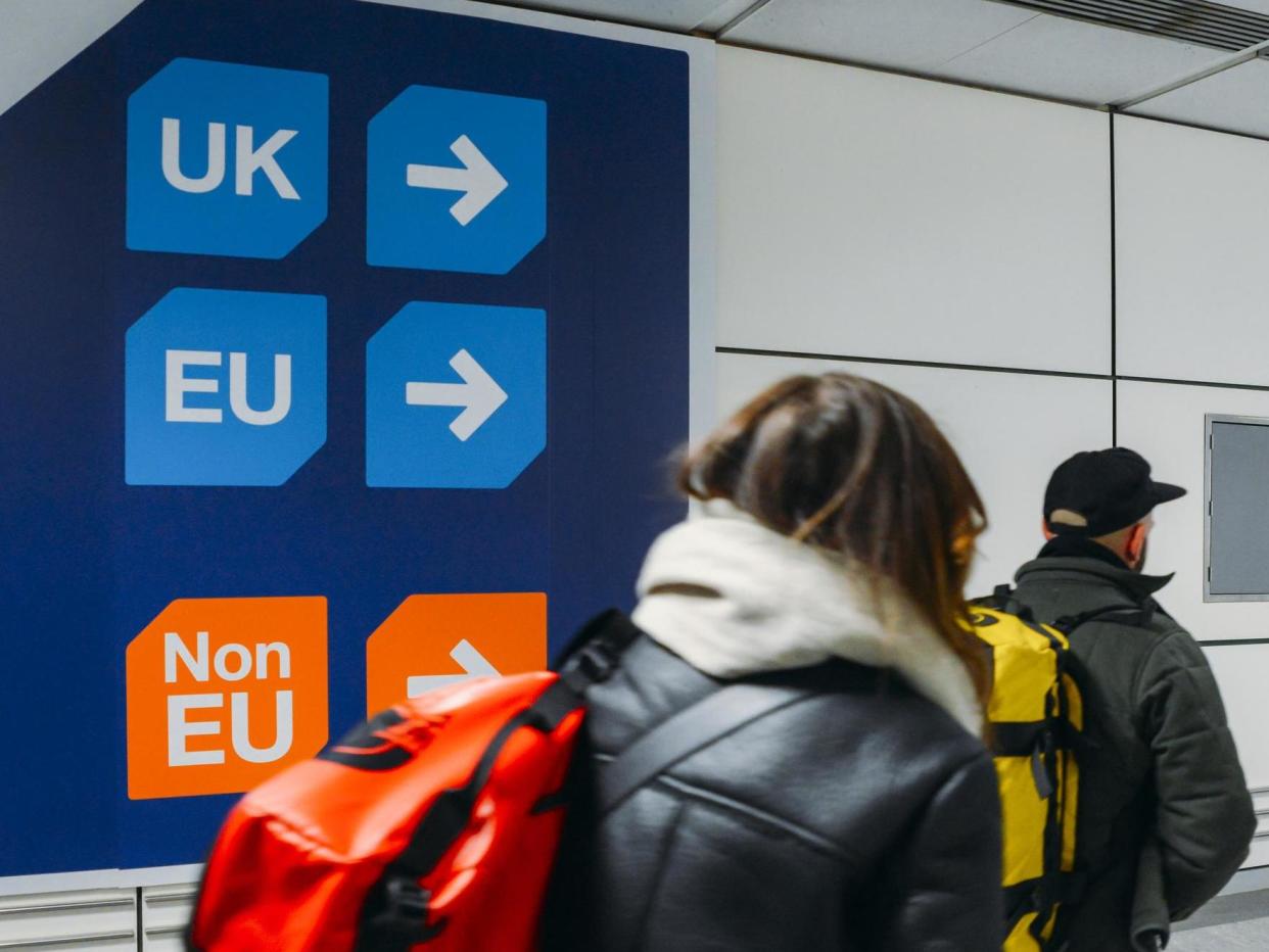 Passengers walk past sign prior to immigration control pointing towards queues for UK, EU and Non-EU passport holders: Getty