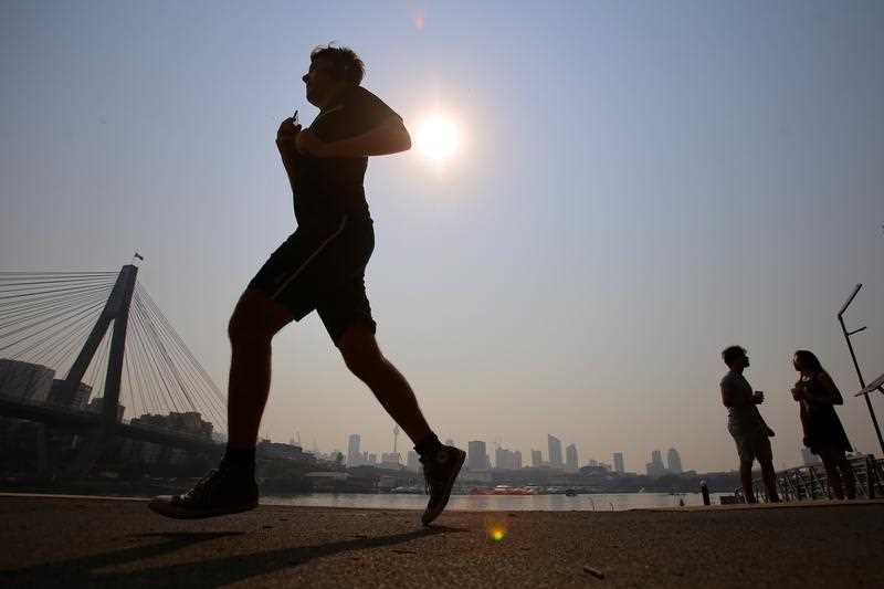 Joggers in Blackwattle Bay as smoke haze from bushfires hangs over the CBD during hot weather in Sydney.