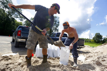 Troy Lukuette (L) and Cayde Lukuette fill sand bags as a response to flood waters in St. Amant, Louisiana. REUTERS/Jonathan Bachman