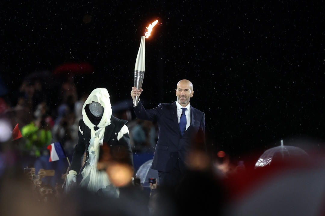 PARIS, FRANCE - JULY 26: Zinedine Zidane, former French football player and manager, holds the torch during the opening ceremony of the Olympic Games Paris 2024 on July 26, 2024 in Paris, France. (Photo by Cameron Spencer/Getty Images)