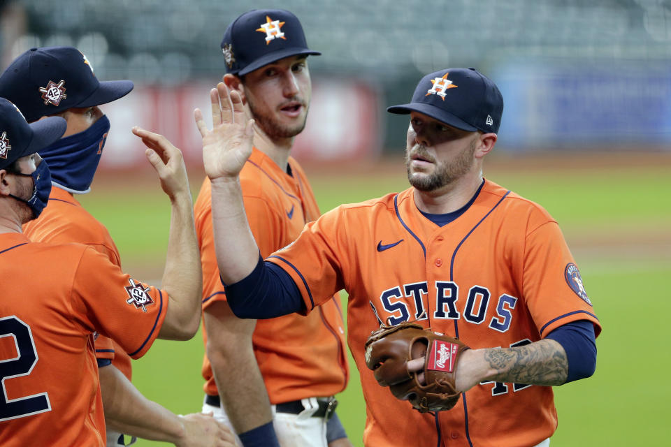 Houston Astros closing pitcher Ryan Pressly, right, collects near high-fives from teammates as Kyle Tucker, rear, watches after the team's 4-2 win over the Oakland Athletics in the first baseball game of a doubleheader Saturday, Aug. 29, 2020, in Houston. All players and managers are wearing No. 42 as a tribute to baseball great Jackie Robinson. (AP Photo/Michael Wyke)
