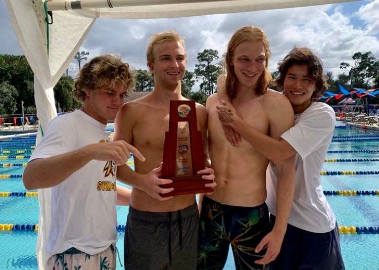 Senior Hudson Bishop, left, points at Jupiter's fourth district trophy since 2018 with teammates at Class 4A-District 5 championships on Friday in Jupiter.