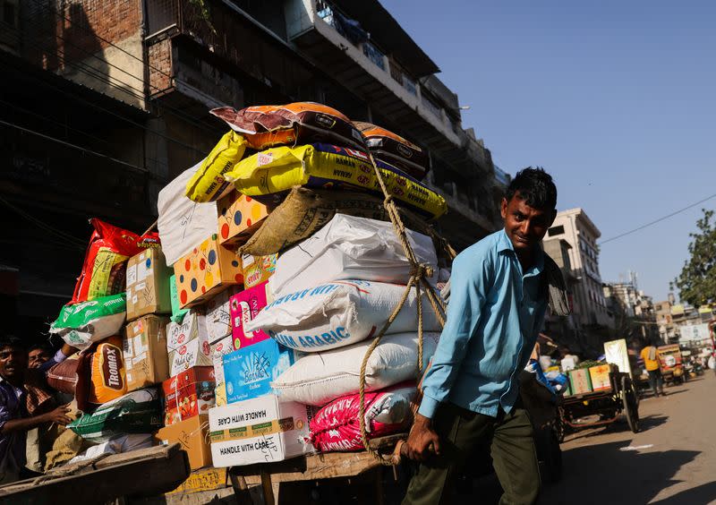 A labourer reacts as he transports a cart full of sacks at a wholesale market in the old quarters of Delhi
