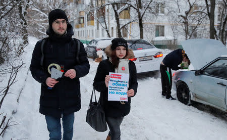 Activists and supporters of Russian opposition leader Alexei Navalny walk near a block of flats as they put up fliers promoting a boycott of the upcoming presidential election in Moscow, Russia February 10, 2018. Picture taken February 10, 2018. The flier reads "March 18. Not election but deceit. Don't let yourself be deceived. Don't go." REUTERS/Maxim Shemetov