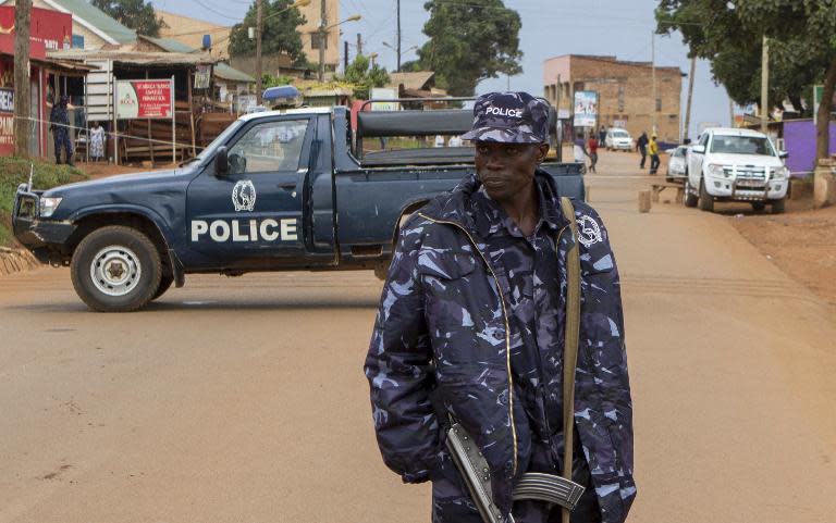 Police stand guard on March 31, 2015 at the scene in a suburb of Uganda's capital Kampala where acting assistant director of public prosecution Joan Kagezi was shot dead