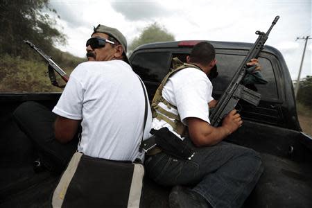 Vigilantes ride on the back of a pick-up truck while driving in a convoy to Poturo December 29, 2013. REUTERS/Jorge Dan Lopez/Files