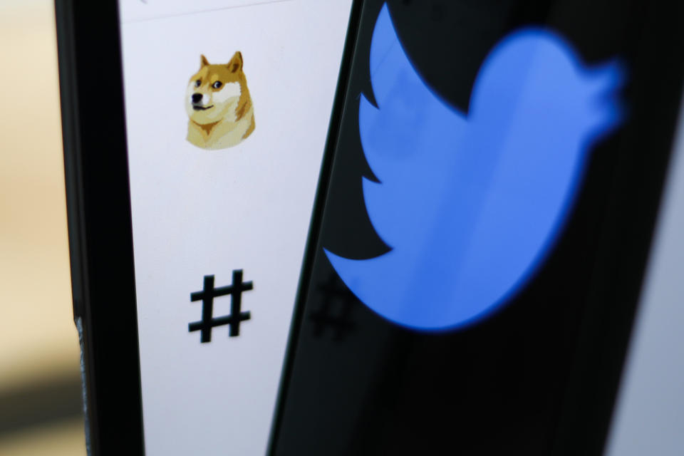 Dogecoin icon on Twitter displayed on a laptop screen and Twitter logo displayed on a phone screen.