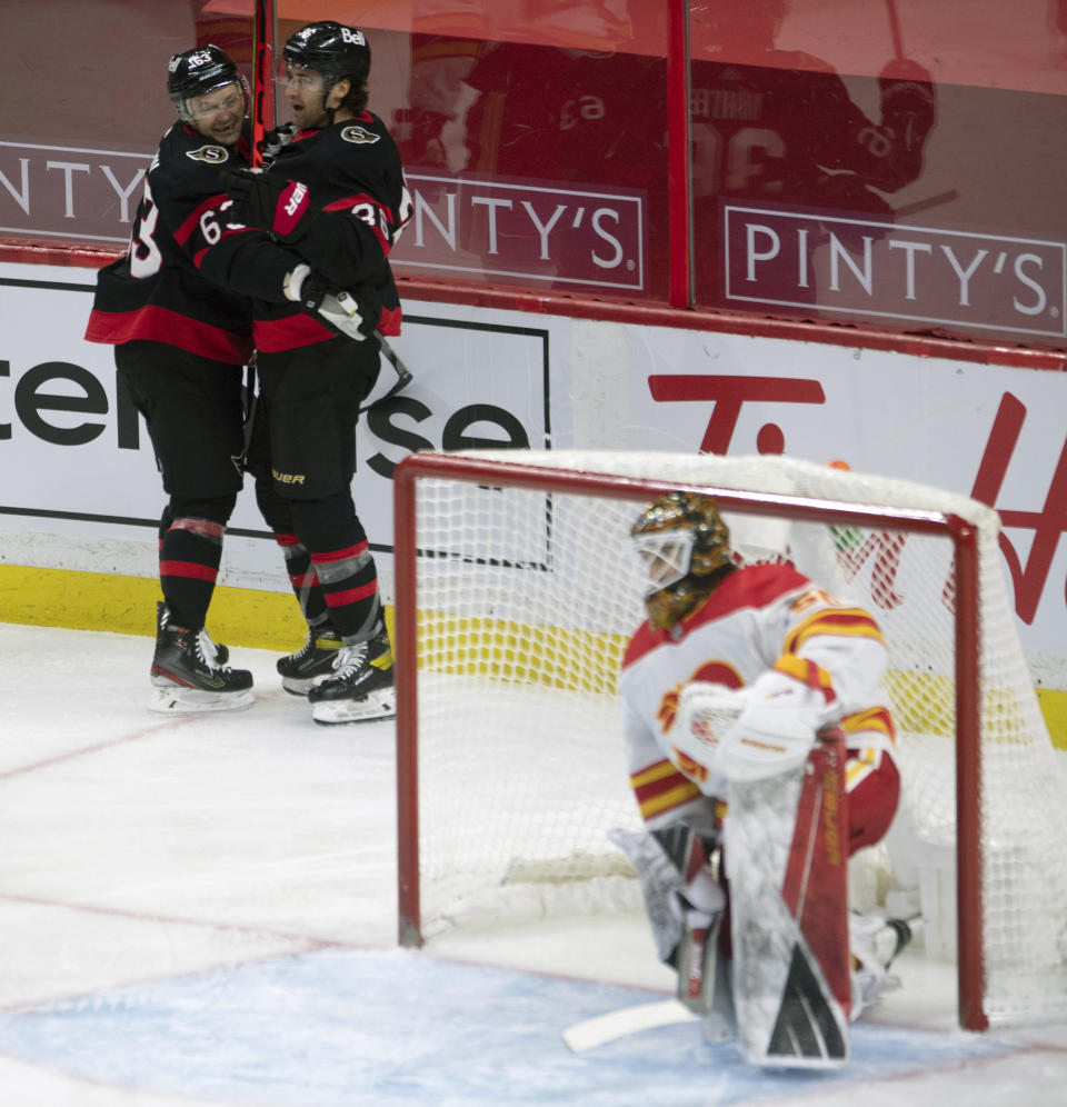 Ottawa Senators center Colin White celebrates his goal with teammate right wing Evgenii Dadonov, left, as Calgary Flames goalie Artyom Zagidulin looks on from his crease during the third period of an NHL hockey game Thursday, Feb. 25, 2021, in Ottawa, Ontario. (Adrian Wyld/The Canadian Press via AP)