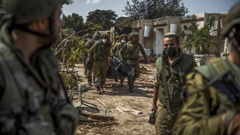 Israeli forces extract dead bodies of Israeli residents from a destroyed house in Kfar Aza on Tuesday. - Ilia Yefimovich/picture-alliance/dpa/AP