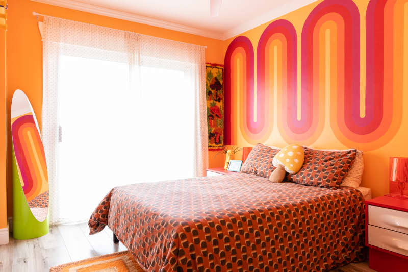 Orange and red decal behind bed in vintage inspired bedroom.