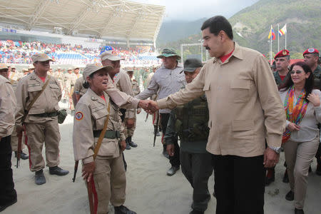 Venezuela's President Nicolas Maduro (front R) shakes hands with a militia member during a military parade, next to his wife and deputy of Venezuela's United Socialist Party (PSUV) Cilia Flores (R) in La Guaira, Venezuela May 21, 2016. Miraflores Palace/Handout via REUTERS