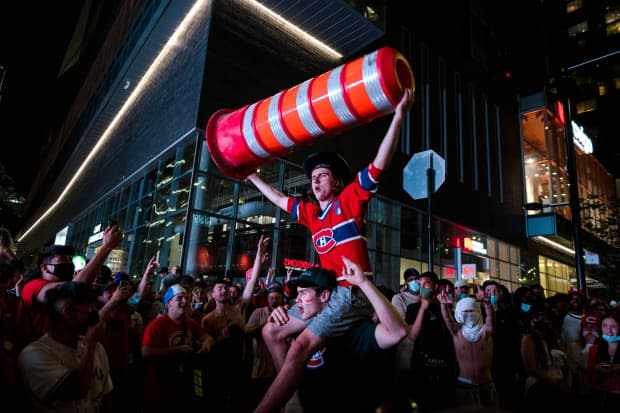 Montreal Canadiens fans raise a traffic cone in a victory celebration. (Andrej Ivanov / AFP via Getty Images - image credit)