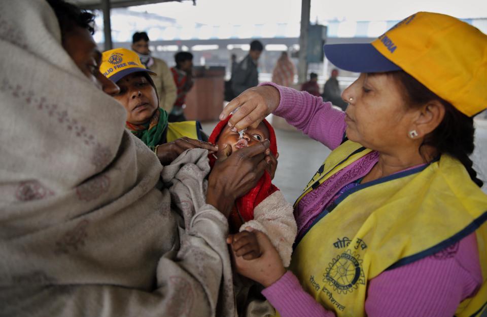 An Indian medical volunteer administers polio immunization drops to a child at a railway station in Allahabad, India, Monday, Jan. 13, 2014. India on Monday marked three years since its last polio case was reported, a major milestone in eradicating the crippling disease. (AP Photo/Rajesh Kumar Singh)