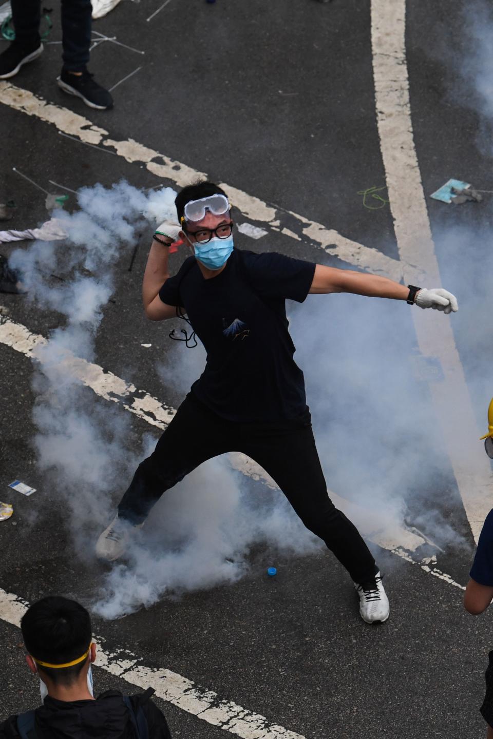 A protester throws back a tear gas during clashes with police outside the government headquarters in Hong Kong on June 12, 2019. - Violent clashes broke out in Hong Kong on June 12 as police tried to stop protesters storming the city's parliament, while tens of thousands of people blocked key arteries in a show of strength against government plans to allow extraditions to China. (Photo by Anthony WALLACE / AFP)        (Photo credit should read ANTHONY WALLACE/AFP/Getty Images)