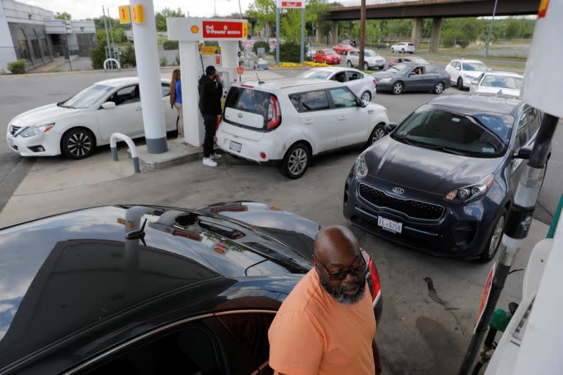 FILE PHOTO: A person fills their car with gas as people queue at a Shell gas station, after a cyberattack crippled the biggest fuel pipeline in the country, run by Colonial Pipeline, in Washington, D.C.