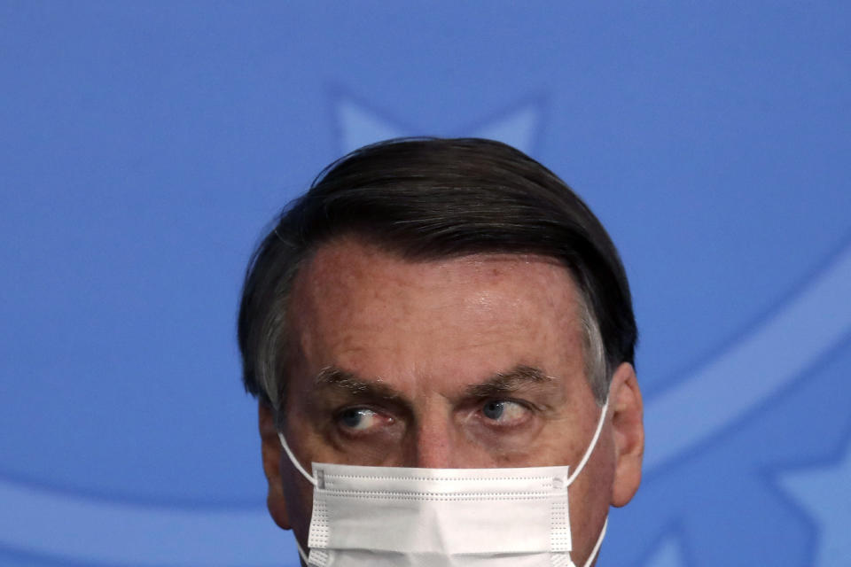 FILE - In this Tuesday, May 18, 2021 file photo, Brazil's President Jair Bolsonaro, wearing a mask to curb the spread of COVID-19, attends the launching ceremony of the Asphalt Giants Program, at the Planalto presidential palace, in Brasilia, Brazil. The coronavirus pandemic has upended life around the globe, but it has hasn’t stopped the spread of authoritarianism and extremism. Some researchers believe it may even have accelerated it, but curbing individual freedoms and boosting the reach of the state. Since COVID-19 hit, Hungary has banned children from being told about homosexuality. China shut Hong Kong’s last pro-democracy newspaper. Brazil’s president has extolled dictatorship. Belarus has hijacked a passenger plane. A Cambodian human rights lawyer calls the pandemic “a dictator's dream opportunity.” But there are also resistance movements, as protesters from Hungary to Brazil take to the streets to defend democracy. (AP Photo/Eraldo Peres, File)