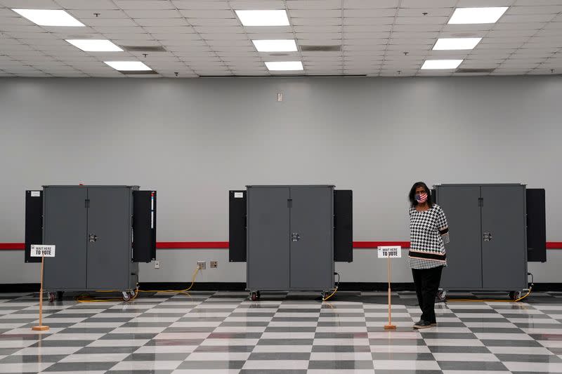 A woman waits to help voters cast their ballots in the U.S. Senate runoff elections on the first day of early voting in Atlanta