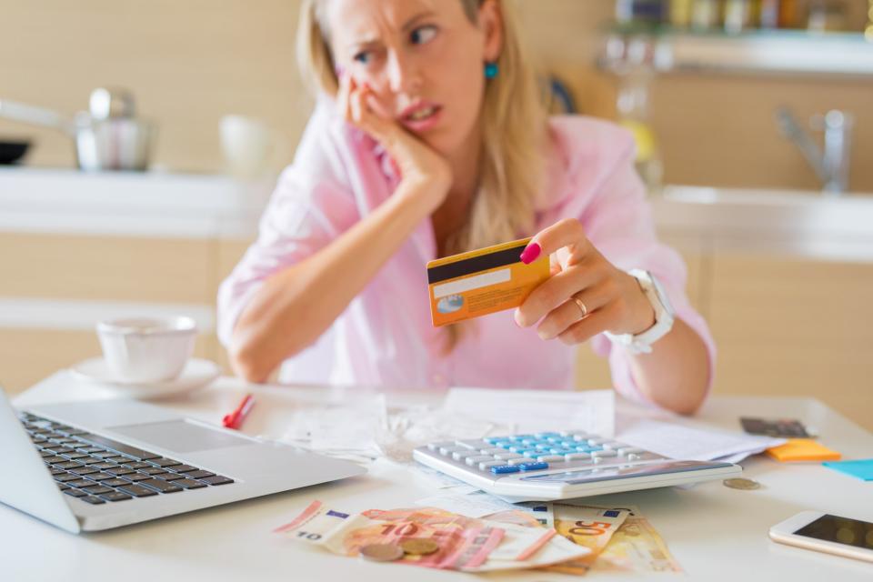 Woman looking at credit card in dismay.