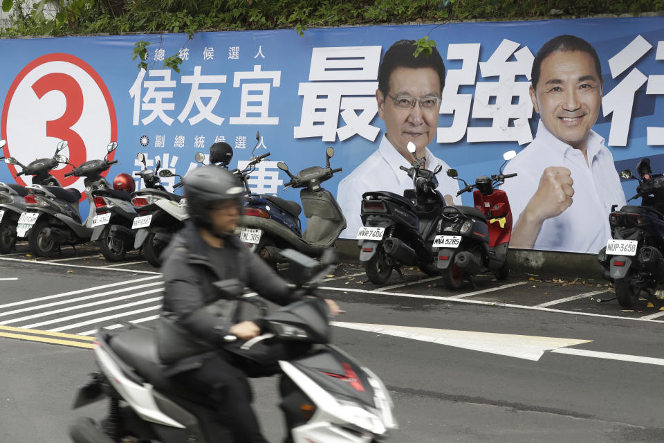 FILE - People pass by a poster of candidates running for the Taiwanese presidential election in Taipei, Taiwan, Saturday, Dec. 30, 2023. Taiwan will hold its presidential election on Jan. 13, 2024. (AP Photo/Chiang Ying-ying, File)