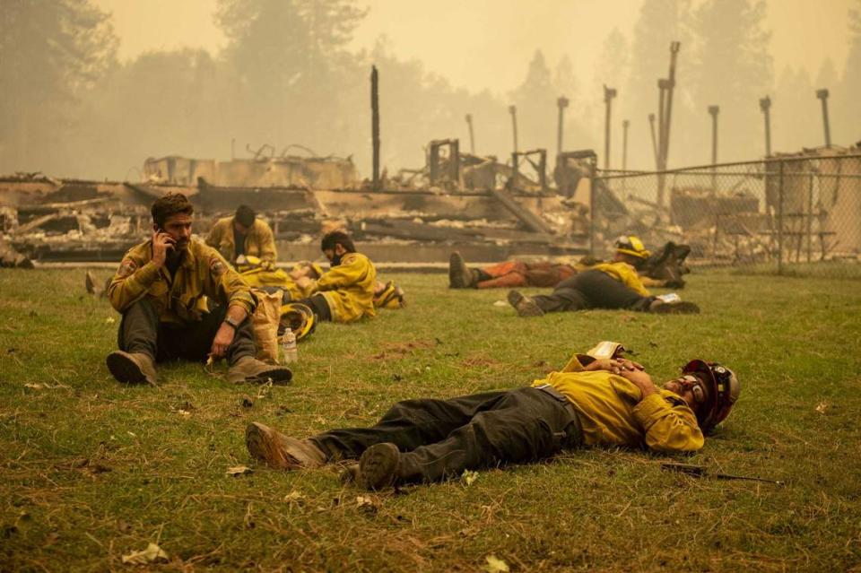 A Cal Fire crew takes a break in the grass next to Berry Creek Elementary School, which was destroyed overnight during the Bear Fire on Wednesday, Sept. 9, 2020. The crews only get a brief window to rest between hourslong shifts. The blaze, part of the larger North Complex burning in Northern California, exploded in size Tuesday night and into Wednesday, forcing evacuation warnings and orders for at least 20,000 people in Butte County and reportedly inflicting widespread damage on the foothill community of Berry Creek.