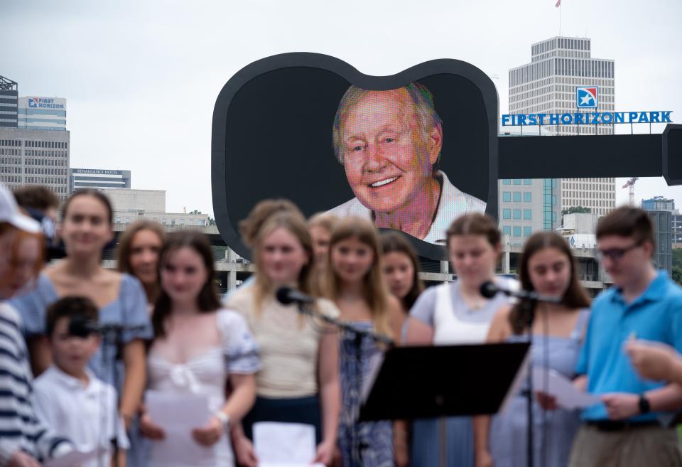 Charlie Strobel's picture adorns the scoreboard as his nieces and nephews perform a song at "A Celebration of Life Honoring Charles Strobel" at First Horizon Park Friday morning, Aug. 11, 2023. The Rev. Charles Frederick Strobel, a native of Nashville, was an advocate for the poor and started Room In The Inn, a shelter for those without homes.
