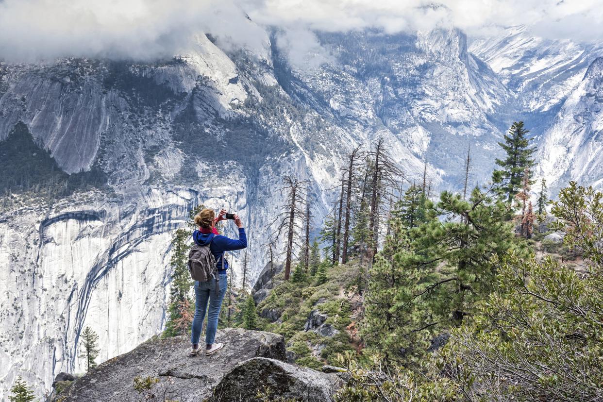 woman with small backpack taking photo of Yosemite