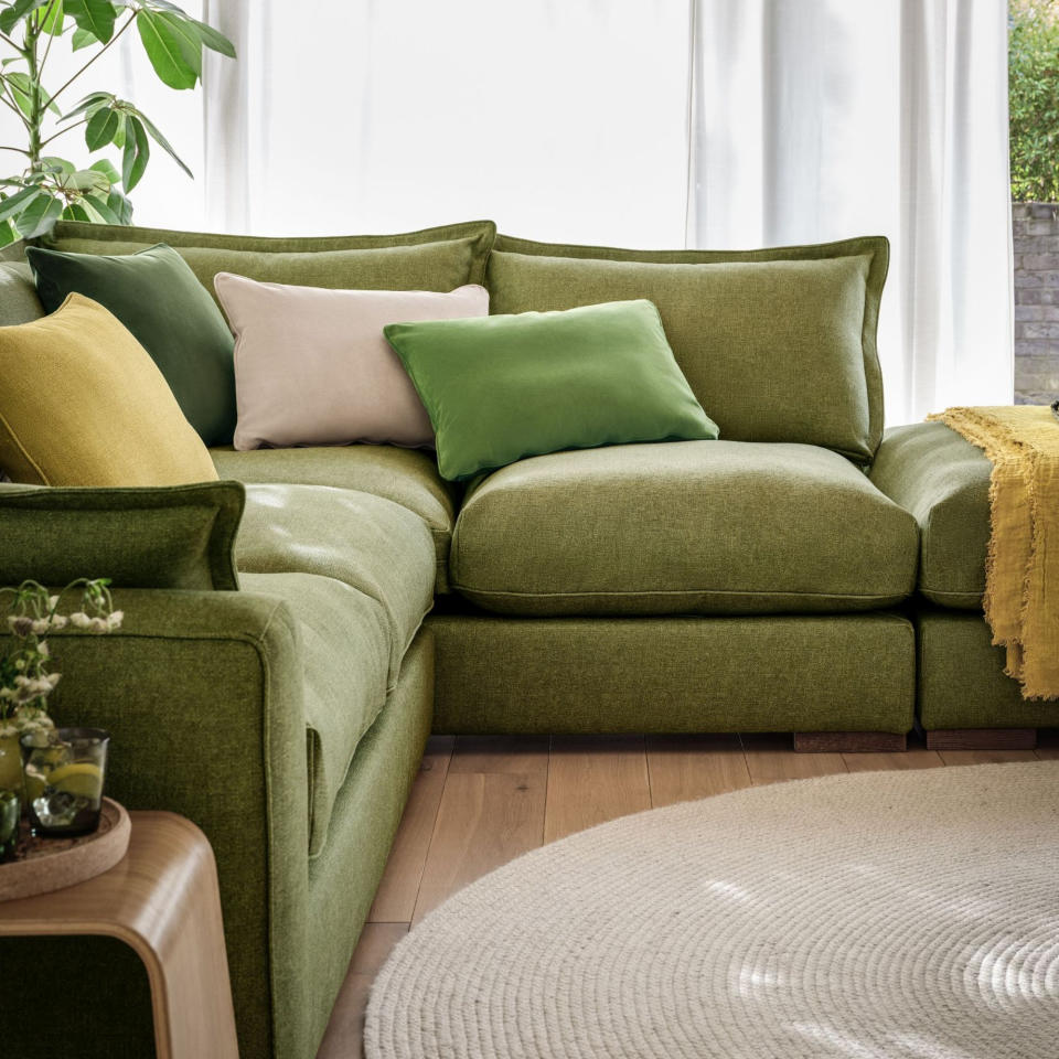 Green modular sofa in living room with cushions