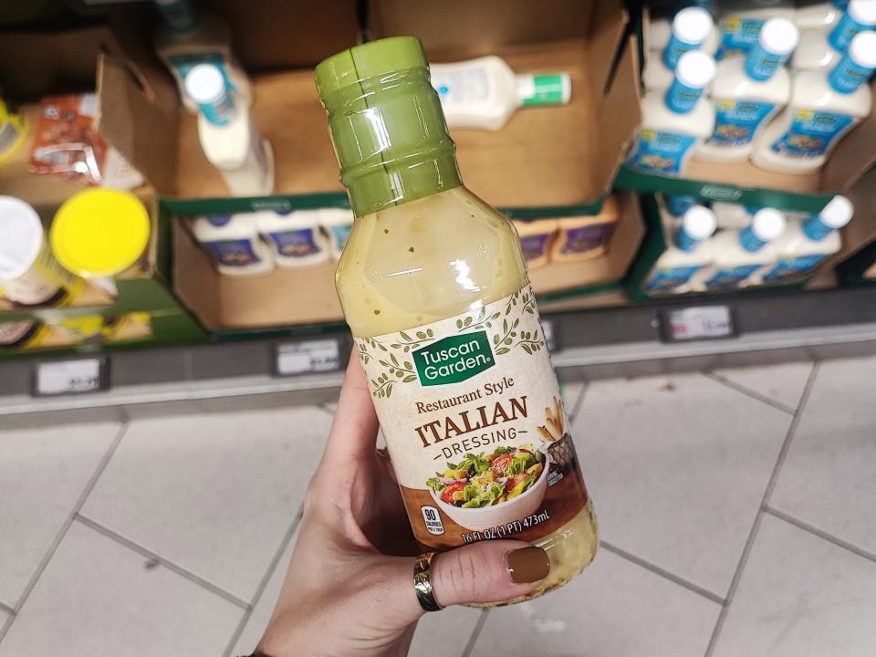 A hand holding a bottle of Tuscan Garden restaurant-style Italian dressing.