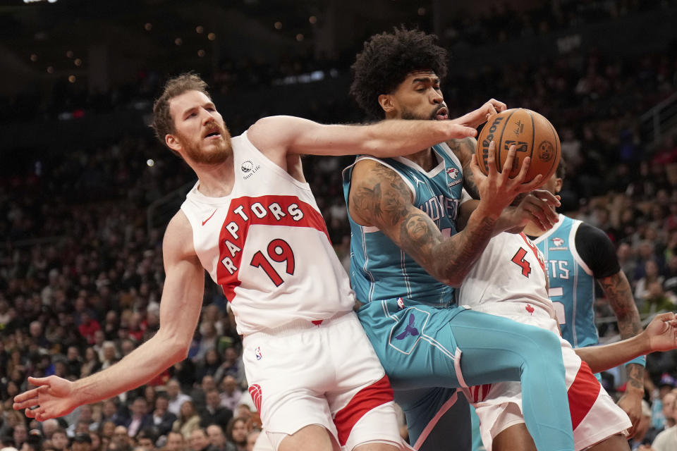 Charlotte Hornets center Nick Richards, front right, and Toronto Raptors center Jakob Poeltl (19) vie for control of the ball during first-half NBA basketball game action in Toronto, Monday, Dec. 18, 2023. (Nathan Denette/The Canadian Press via AP)