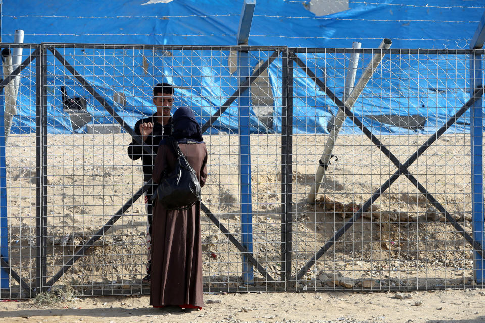 A displaced woman speaks with her husband through a fence at Deepaka camp