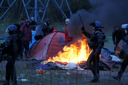 A burning tent is seen, as French riot police push back Iranian Kurdish migrants, during the dismantling of a camp in Calais, France, January 10, 2019. Picture taken January 10, 2019. REUTERS/Pascal Rossignol