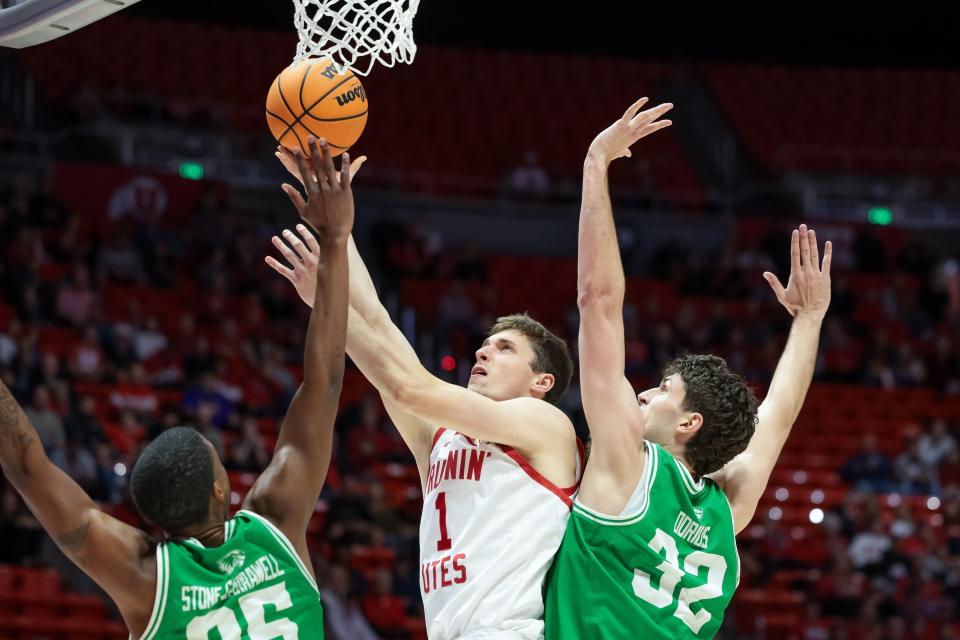 Utah Utes forward Ben Carlson (1) goes to the hoop against Utah Valley Wolverines forward Caleb Stone-Carrawell (25) and center Trevin Dorius (32) at the Huntsman Center in Salt Lake City on Saturday, Dec. 16, 2023. | Spenser Heaps, Deseret News