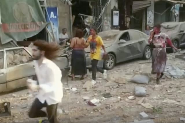 People walk down the street after an explosion in Beirut (AP)