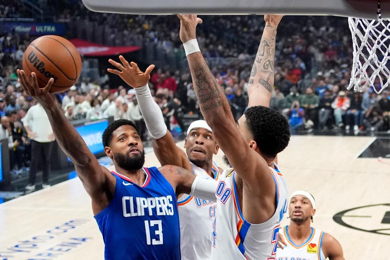 Los Angeles Clippers forward Paul George, left, shoots as Oklahoma City Thunder guard Shai Gilgeous-Alexander, center and forward Kenrich Williams defend during the first half of an NBA basketball game Tuesday, Jan. 16, 2024, in Los Angeles. (AP Photo/Mark J. Terrill)