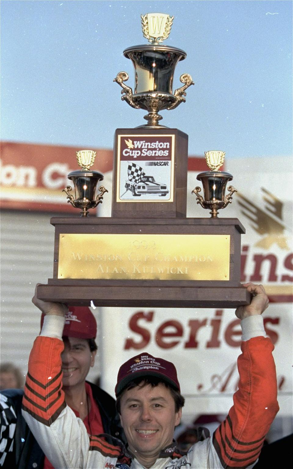 FILE - In this Nov. 16, 1992, file photo, driver Alan Kulwicki holds the NASCAR Winston Cup Championship trophy over his head in Victory Lane after he won the championship at Atlanta Motor Speedway in Hampton, Ga. Kulwicki is being inducted into the NASCAR Hall of Fame on Friday, Feb. 1, 2019. (AP Photo/John Bazemore, File)