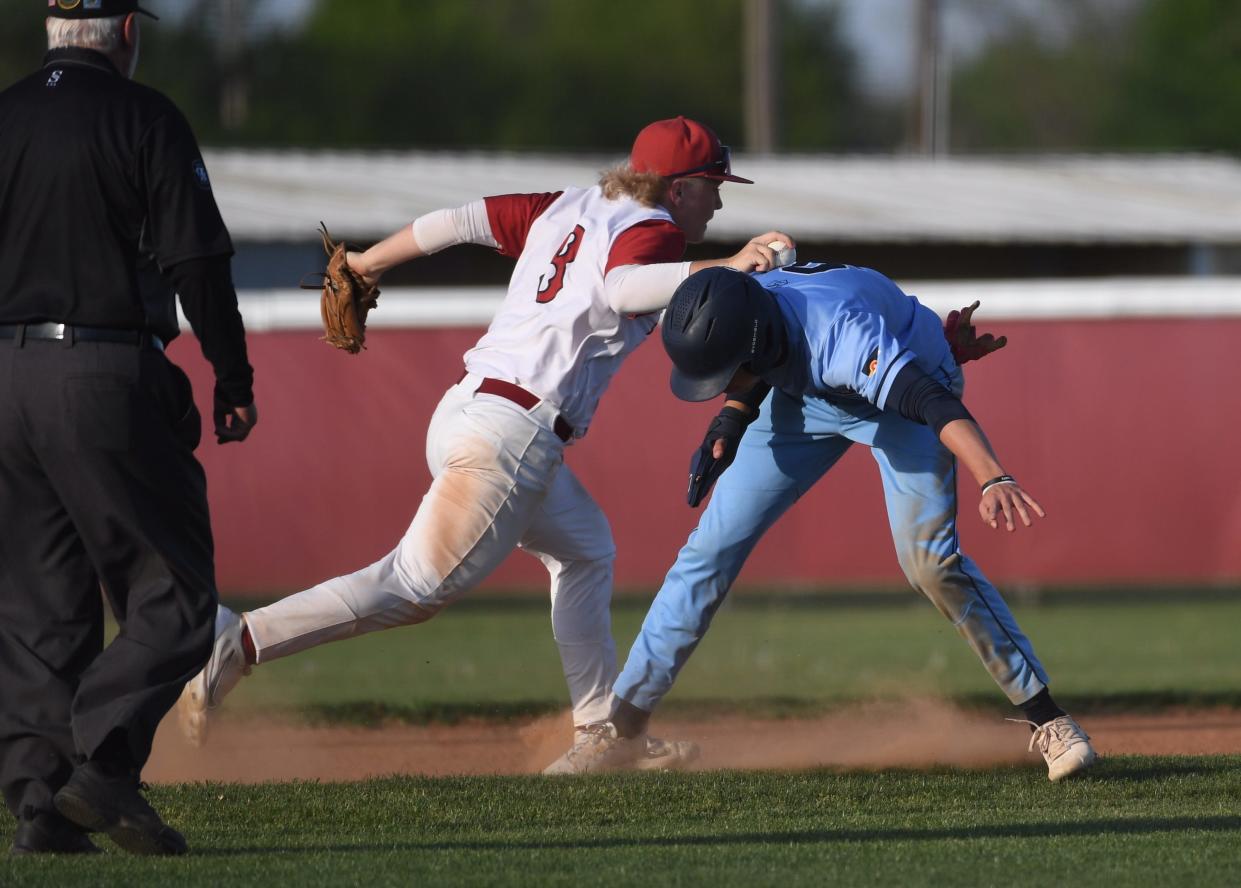 Dewey High School's third baseman Parker Garrison (8) tags out a Casica Hall runner in Dewey on April 19, 2024.