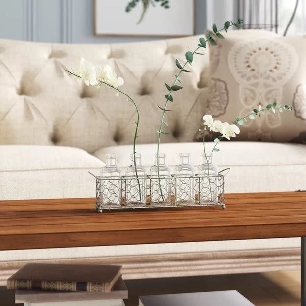 Flowers in glass vases on a wooden table in a living room