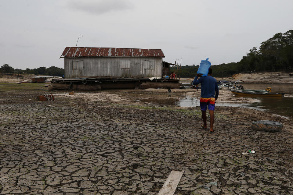 FILE - Jonathan Ciqueira Cavalcante carries water across the dry riverbed of the Negro River to his house boat that used to float, during a drought in Manaus, Amazonas state, Brazil, Monday, Oct. 16, 2023. Human-induced global warming was the primary driver of last year's severe drought in the Amazon that sent rivers to record lows, researchers said Wednesday, Jan. 24, 2024. (AP Photo/Edmar Barros, File)