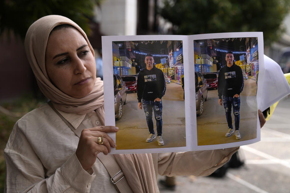 Dalia Elghaty, the aunt of a 27 year-old Egyptian, who he is accused of causing a shipwreck, holds photos of him outside a court house in Kalamata, southwestern Greece, on Tuesday, May 21, 2024. Nine Egyptian men have gone on trial in southern Greece, accused of causing a shipwreck that killed hundreds of migrants and sent shockwaves through the European Union's border protection and asylum operations. (AP Photo/Thanassis Stavrakis)