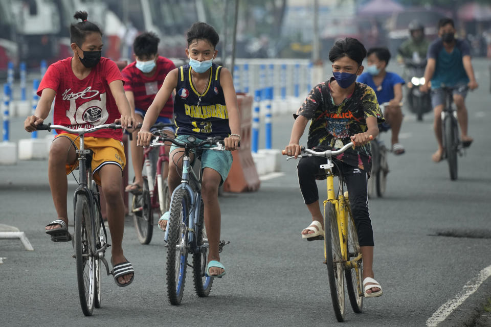 Boys wearing face masks to prevent the spread of the coronavirus ride their bikes outside Manila's COVID-19 Field Hospital, Philippines on Thursday, Sept. 2, 2021. The Philippines has recorded over two million COVID-19 cases as infections continue to rise in the country. (AP Photo/Aaron Favila)